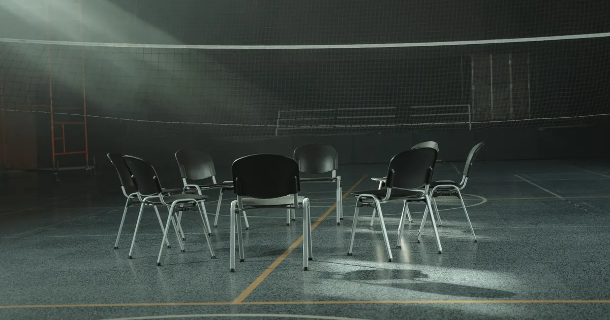 Empty chairs arranged in a circle in a room lit by sunlight