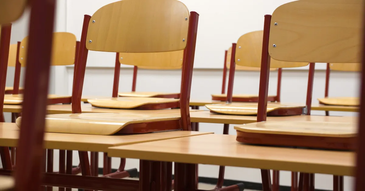 Rows of wooden chairs and desks in an empty classroom