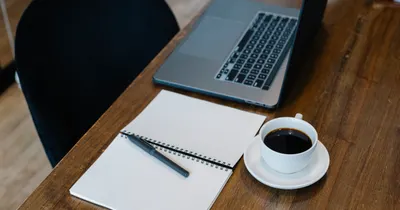 Notebook, laptop and coffee cup on a wooden desk