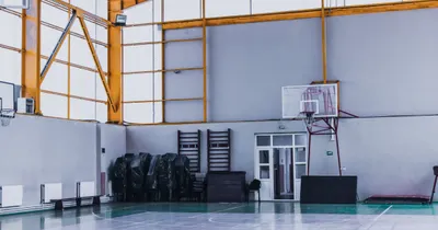An empty sports hall with a basketball hoop and exercise equipment