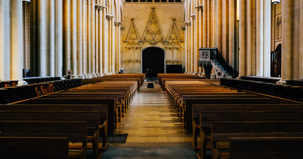 Empty wooden pews beneath tall arches inside a cathedral