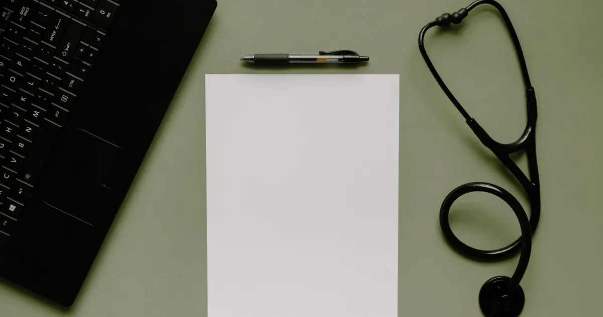 A blank clipboard, pen and stethoscope on a medical workspace
