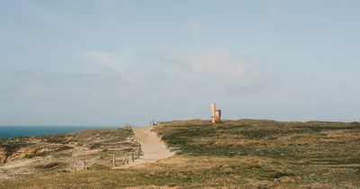 An open coastal footpath under a pale blue sky