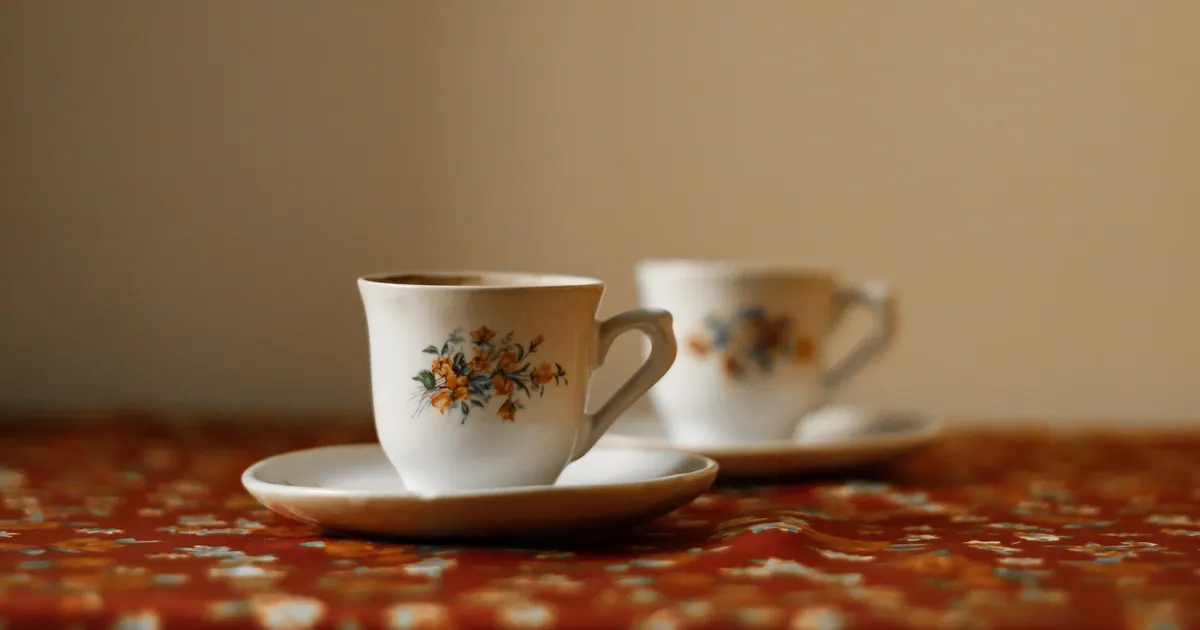 Two floral teacups on a patterned tablecloth