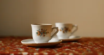 Two floral teacups on a patterned tablecloth