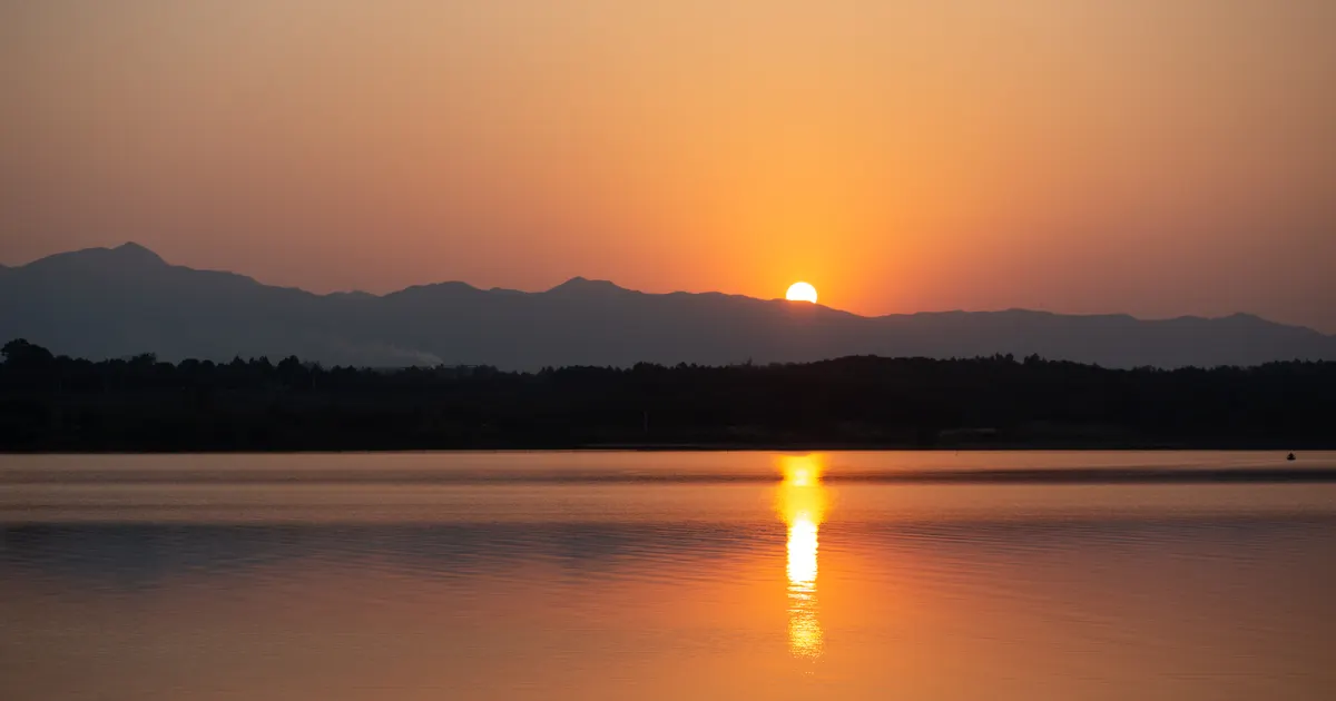 Sunset reflected on a calm lake beneath distant mountains