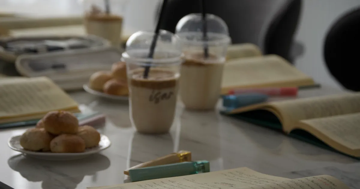 Open notebooks, iced coffee and snacks on a study table