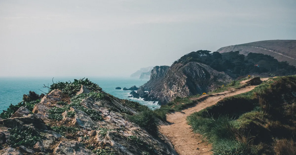 A walking path along rocky cliffs overlooking the sea