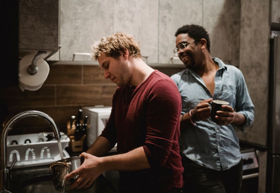 Two housemates talking while sharing kitchen chores at home