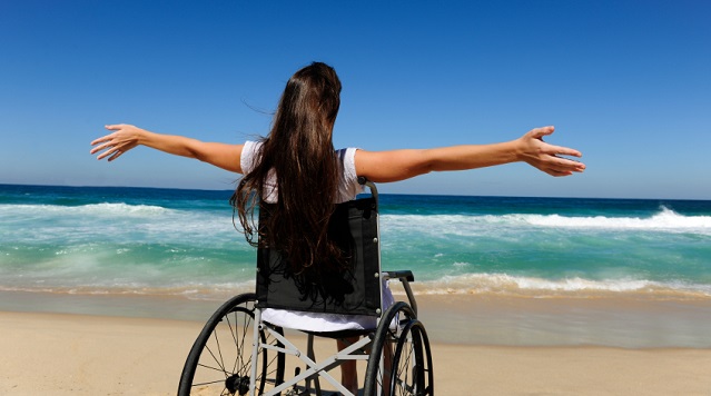 woman in wheelchair enjoying summer vacation on the  beach